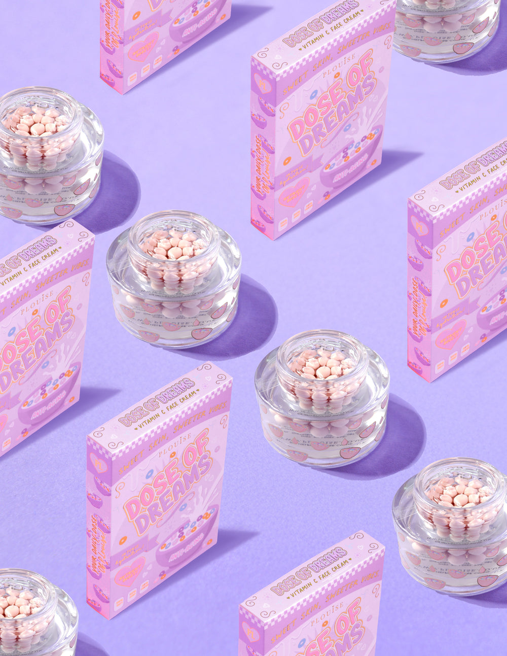 Envases transparentes de P.Louise DOse of Dreams Viatmin C Capsule Face Cream con una cápsula rosa rodeada de cajas de cereales rosas sobre un fondo morado