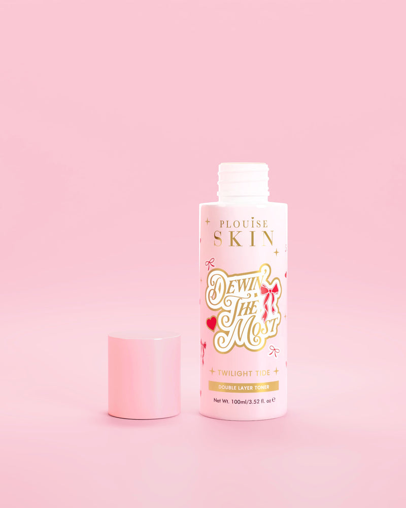 Frasco rosa de P.Louise Dewin The MOst Double Layer Toner com desenhos de laço vermelho contra um fundo rosa