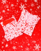 Par de pijama listrado rosa e branco com desenhos de laço festivo vermelho em um fundo vermelho com flocos de neve