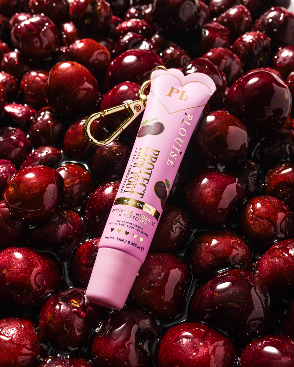 Condicionador labial com aroma de cereja preta rosa protege seu beicinho com clipe dourado em uma cama de cerejas