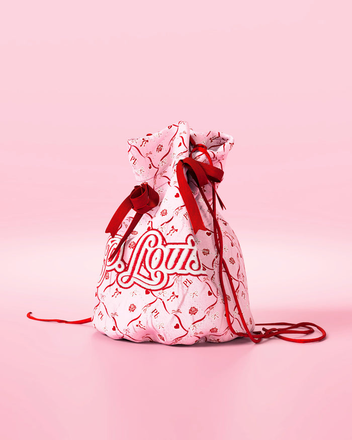 Bolsa com cordão rosa com laços vermelhos e design festivo com a marca 'P.Louis' em fundo rosa
