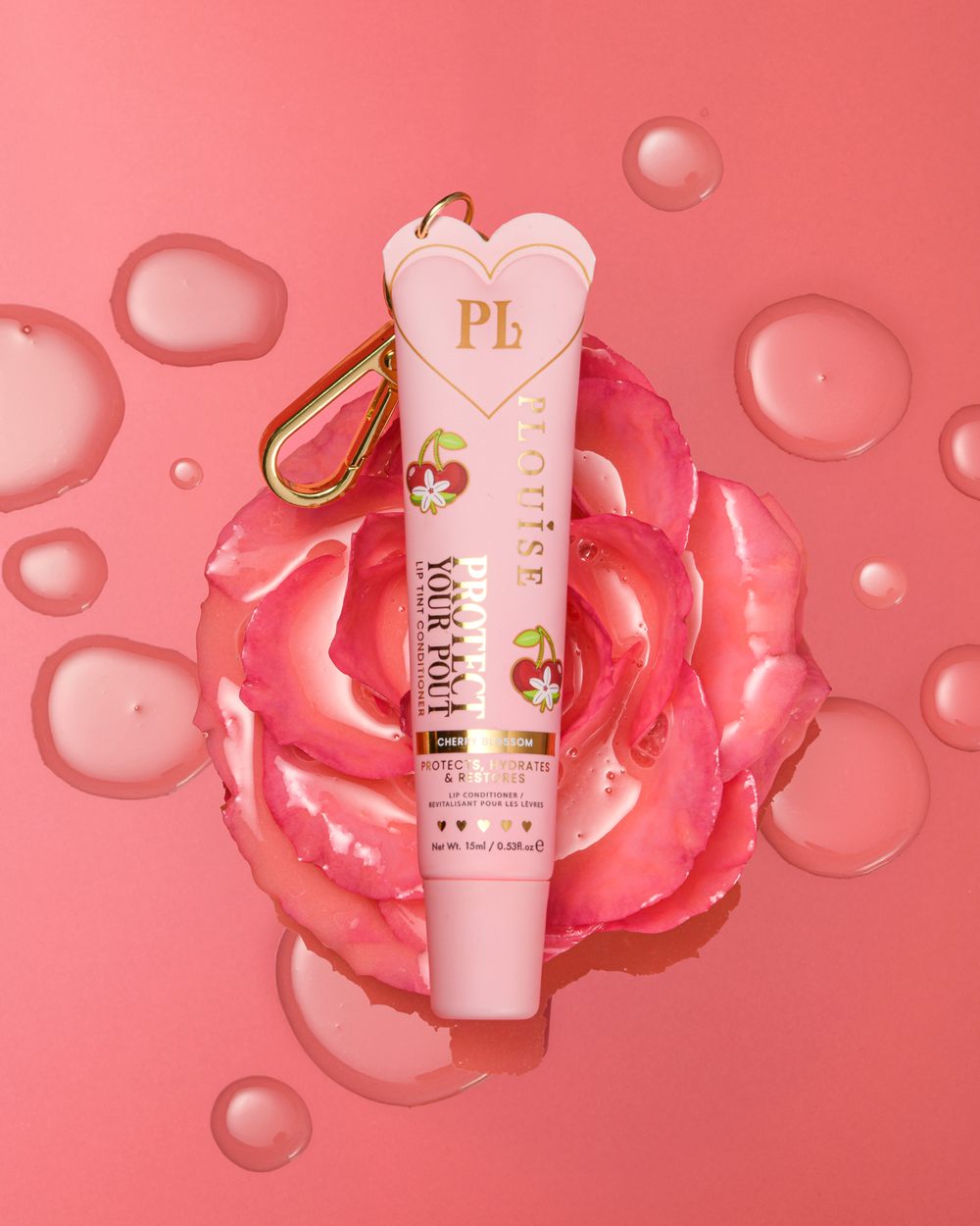 Condicionador labial com aroma de flor de cerejeira rosa protege seu beicinho com clipe dourado em cima de uma flor rosa