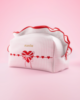 Uma bolsa de maquiagem e cuidados com a pele P.Louise listrada rosa e branca com babados e desenho de coração de amor sobre um fundo rosa