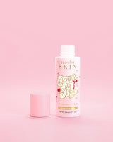 Botella rosa de P.Louise Dewin The MOst Double Layer Toner con diseños de lazos rojos sobre un fondo rosa 