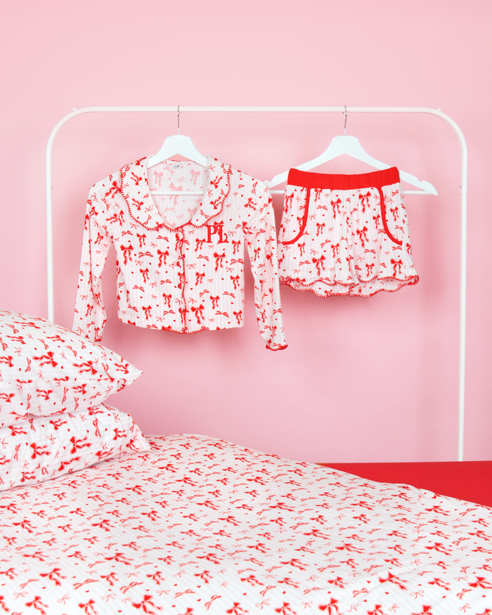 Conjunto de shorts de pijama listrados rosa e branco para meninas P.Louise Natal em cabides em um quarto rosa com roupa de cama combinando 