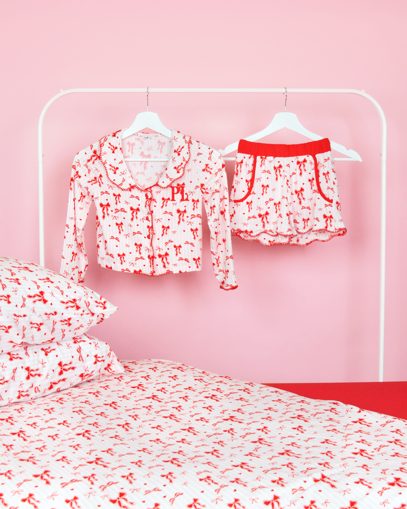 Conjunto de shorts de pijama listrados rosa e branco para meninas P.Louise Natal em cabides em um quarto rosa com roupa de cama combinando 