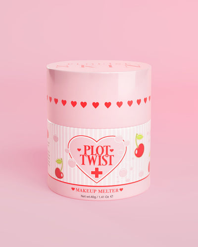 Um recipiente rosa de P.Louise Plot Twist Makeup Melting Cleansing Balm com desenhos de coração e cereja no rótulo contra um fundo rosa