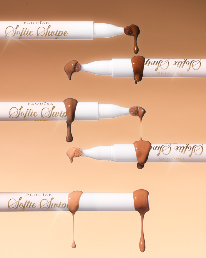Una imagen de cinco mascarillas de labios teñidas Softie Swipe de P.Louise con el producto goteando de las puntas que muestran los distintos tonos sobre un fondo beige.