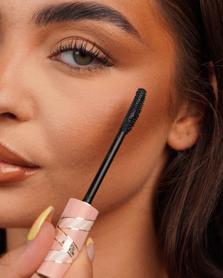 Close-up of a P.Louise Tearproof mascara wand held near a person's eye with a blurred background