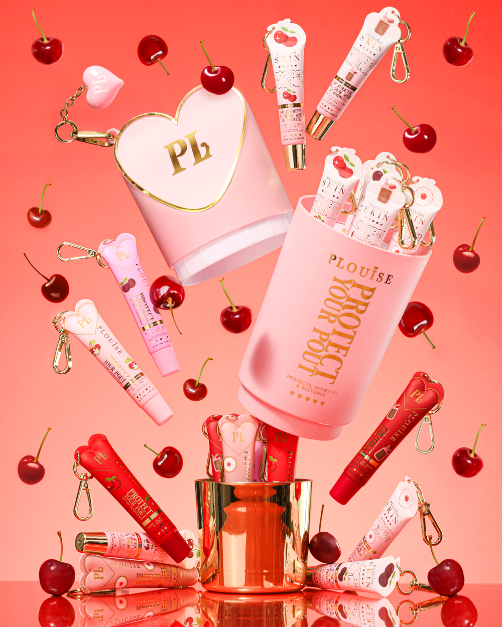 Conjunto de presente Pink XL Protect Your Pout que é aberto cercado por cerejas e condicionadores labiais rosa e vermelhos em um fundo rosa