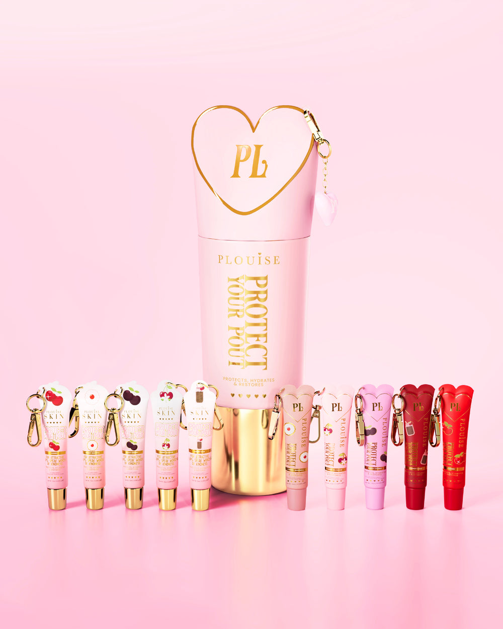 Conjunto de condicionadores labiais com aroma de cereja rosa e vermelho com um rosa e dourado proeminente protegendo seu frasco de beicinho no centro em um fundo rosa.