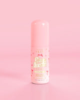 Frasco rosa de P.Louise Pure Intentions Purify & Brightening Lotion com desenhos de laço vermelho contra um fundo rosa