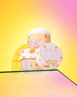 Tres recipientes de manteca corporal de mango P. Louise 'Lift It On Thick' sobre un fondo amarillo y rosa degradado