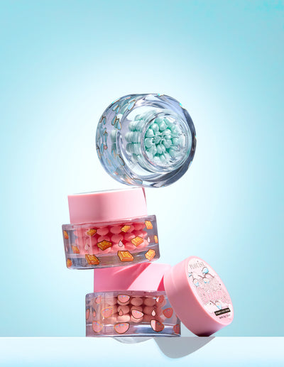 Três pequenos frascos com cápsula colorida de vitamina C em gel sobre fundo azul claro