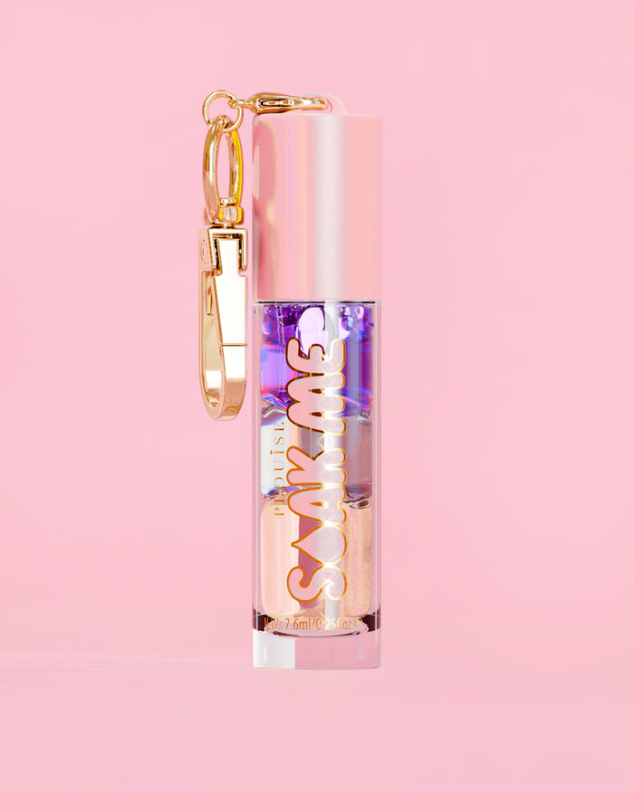 P. Louise Soak Me Lip Oil com óleo colorido em camadas em um tubo rosa com fecho dourado sobre fundo rosa
