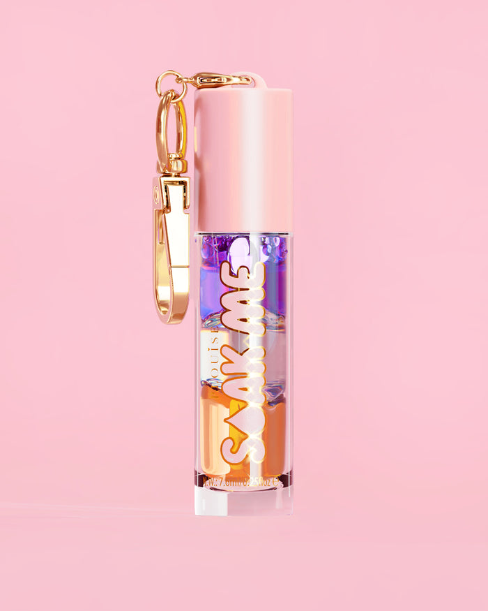P. Louise Soak Me Lip Oil com óleo colorido em camadas em um tubo rosa com fecho dourado sobre fundo rosa