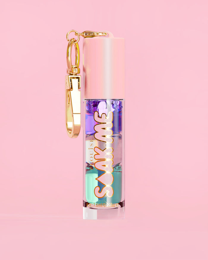 P. Louise Soak Me Lip Oil com óleo colorido em camadas em um tubo rosa com fecho dourado sobre fundo rosa