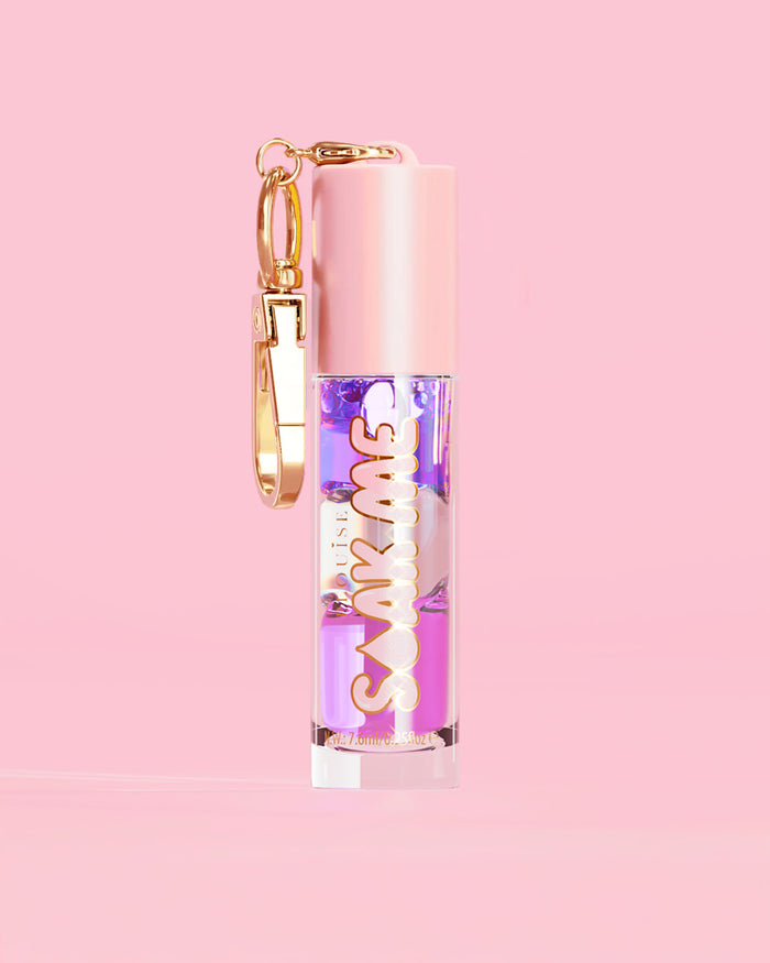 P. Louise Soak Me Lip Oil com óleo colorido em camadas em um tubo rosa com fecho dourado sobre fundo rosa