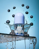 Frasco de P. Louise Clear The Air Blueberry Gel Cleanserl cercado por mirtilos e respingos de água em um fundo azul