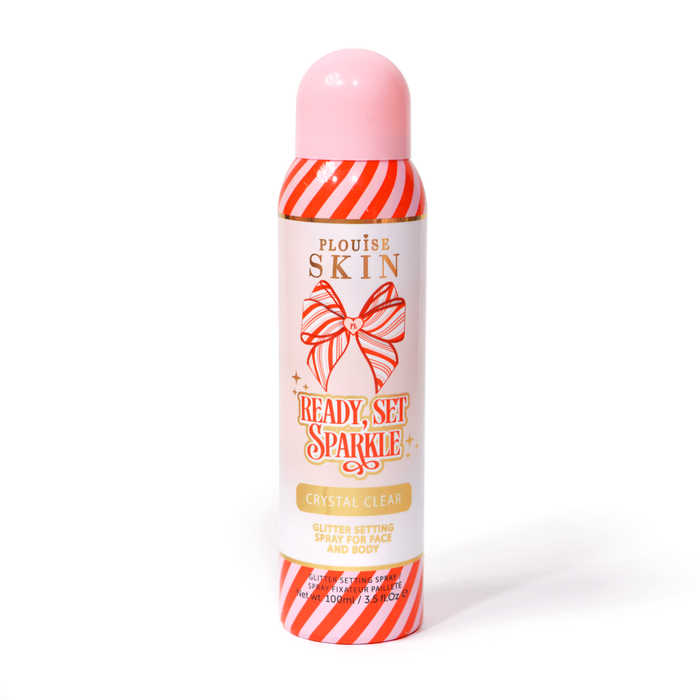 Um frasco de P. Louise Ready Set Sparkle Christmas Glitter Setting Spray com listras vermelhas e rosa no frasco e um laço listrado vermelho e rosa contra um fundo branco