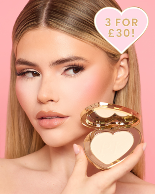 Woman holding a P.Louise heart-shaped compact containing an under-eye brightening & pressed powder