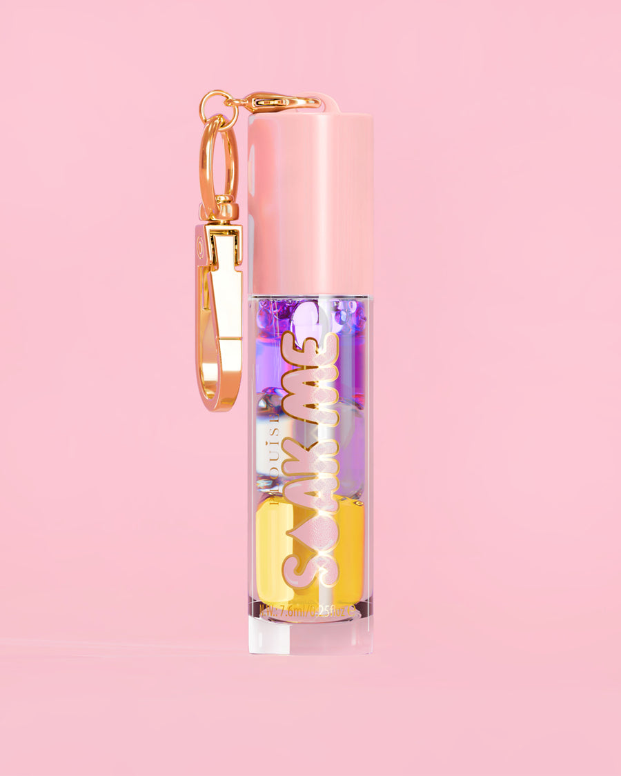 P. Louise Soak Me Lip Oil com óleo colorido em camadas em um tubo rosa com fecho dourado sobre fundo rosa