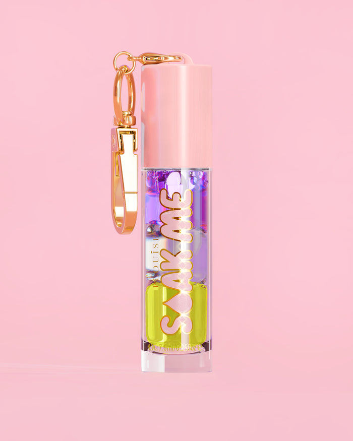 P. Louise Soak Me Lip Oil com óleo colorido em camadas em um tubo rosa com fecho dourado sobre fundo rosa