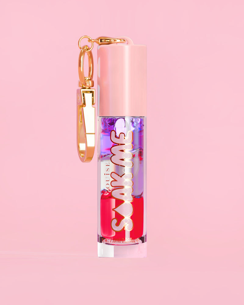 P. Louise Soak Me Lip Oil com óleo colorido em camadas em um tubo rosa com fecho dourado sobre fundo rosa