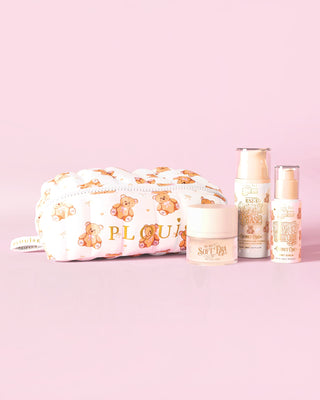 Uma imagem do kit inicial de cuidados com a pele P.Louise Softest Touch com uma bolsa de maquiagem e cuidados com a pele de ursinho de pelúcia com estampa grande e 3 produtos para a pele em um fundo rosa