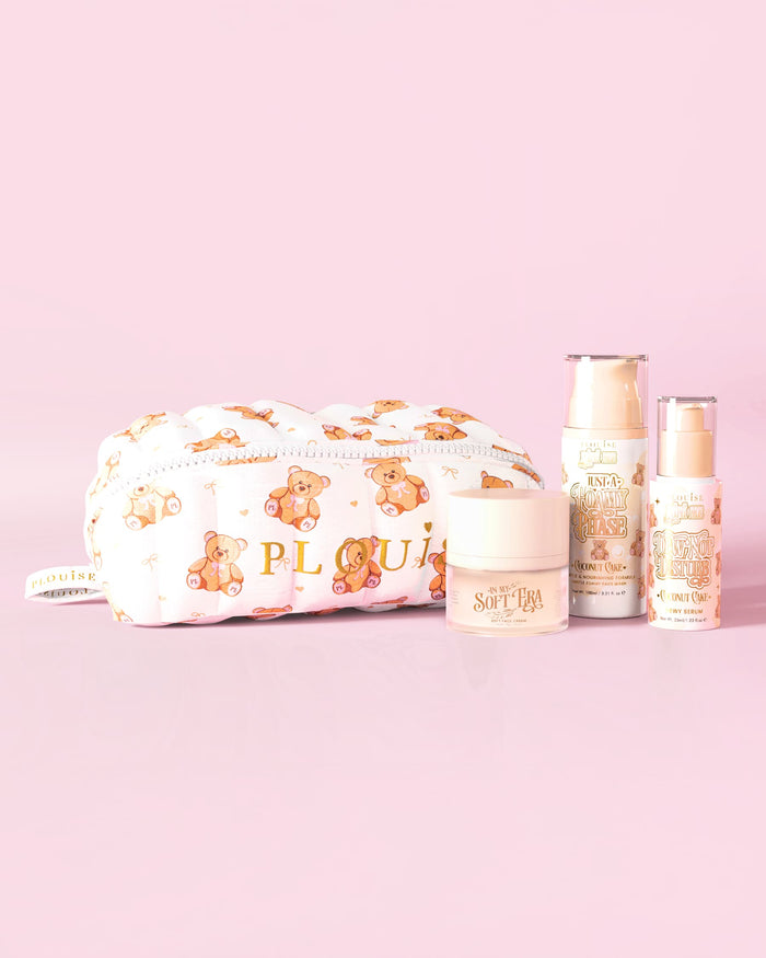 Una imagen del kit básico de cuidado de la piel Softest Touch de P.Louise con una bolsa de maquillaje y cuidado de la piel con un osito de peluche con estampado grande y 3 productos para el cuidado de la piel sobre un fondo rosa.