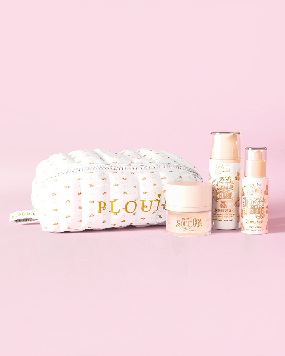 Una imagen de P.Louise The Softest Touch Skincare Starter Kit con un osito de maquillaje con estampado pequeño y una bolsa para el cuidado de la piel que incluye 3 productos para el cuidado de la piel sobre un fondo rosa.